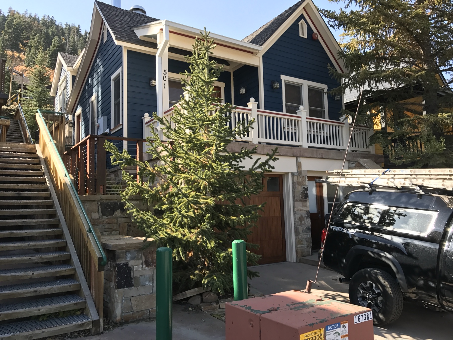 Hillside cottage repainted deep blue with white trim, stone retaining wall and timber deck