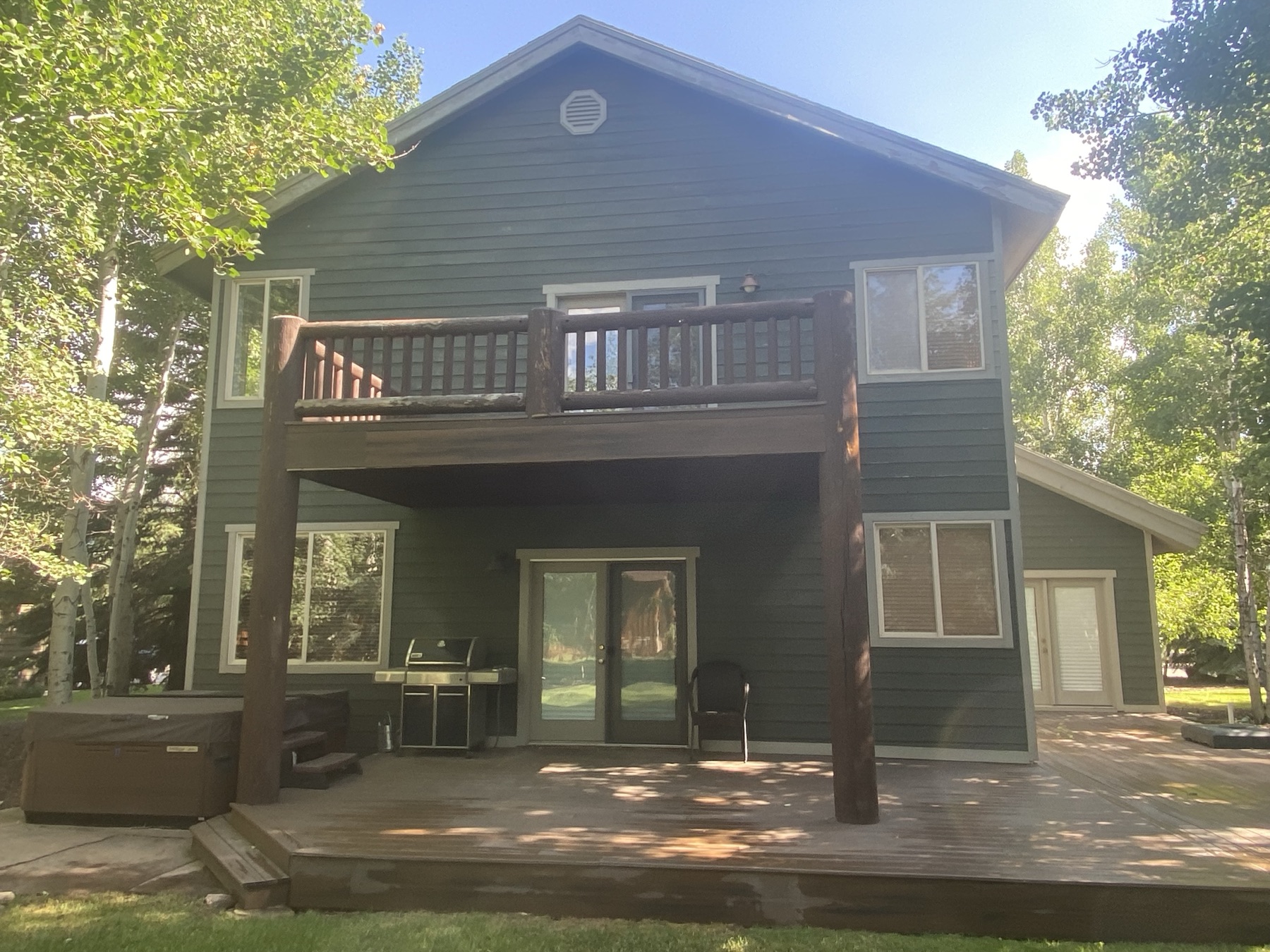 Freshly repainted two-storey home with a log-railed deck among the aspens